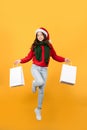 Asian woman in red Christmas sweater and hat holds shopping bags on yellow background Royalty Free Stock Photo