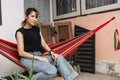 Woman relax on the hammock outside of her house in summer. Staycation concept.