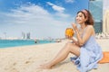 Asian woman is relaxing on the beach in Dubai and drinking a delicious drink and coconut cocktail . Holiday and beverage