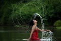 Asian woman relaxing and enjoying playing with water and splash at tropical exotic river with turquoise amazing color water in bea