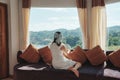 Asian woman relaxing and enjoying the tropical forest view on sofa at panorama room in bright day Royalty Free Stock Photo