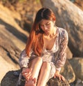 Asian woman is relaxing on a rock on a Sunny Beach for Summer vacation relaxation and hapiness concept