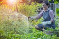 Asian woman relaxing and watering in home garden