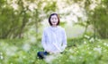 Asian woman is relaxingly practicing meditation yoga in the forest full of daisy flower in summer to attain happiness from inner