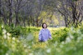 Asian woman is relaxingly practicing meditation yoga in the forest full of daisy flower in summer to attain happiness from inner