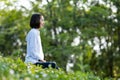 Asian woman is relaxingly practicing meditation yoga in forest full of wild flower in summer to attain happiness from inner peace