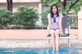 Asian Woman Resting at Poolside with Both Feet on The Water