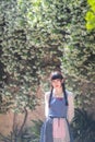 Asian women in retro long dress standing in a French ancient town against old wall background with white flowers, Eze, France