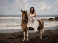 Asian woman riding horse on the beach. Outdoor activities. Woman wearing long white dress. Traveling concept. Cloudy sky. Copy Royalty Free Stock Photo