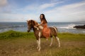 Asian woman riding horse near the ocean. Outdoor activities. Wcuddling her horse. Traveling concept. Copy space. Bali Royalty Free Stock Photo