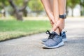 Asian woman runner has ankle sprain, legs have problem. woman hand massaging her leg pain,feel ache injury after exercise in