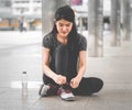 Asian woman runner taking a break and tighting shoes lace Royalty Free Stock Photo