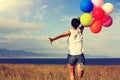 Asian woman running on grassland with colored balloons Royalty Free Stock Photo