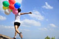 Asian woman running on mountain peak rock with colored balloons