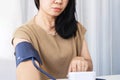 Asian woman self checking blood pressure with machine at home Royalty Free Stock Photo