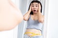 Asian woman shocked with weight gain after checking her fat belly by measuring tape Royalty Free Stock Photo
