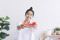 Asian woman showing bitten red watermelon  in kitchen. Asian woman holding watermelon in the kitchen. Woman eating fresh Royalty Free Stock Photo