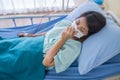 Asian woman is sick has a high fever, sneezing, is recuperating in the patient`s dress lay on the patient bed in the hospital wit