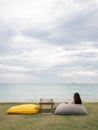 Asian woman sitting on bean bag in garden near the beach. female looking out the sea view. rear view. Royalty Free Stock Photo