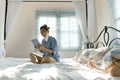 Asian woman sitting on bed with face protection mask touching on social media device