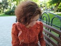 Asian woman sitting on bench looking down. Pretty young multicultural woman enjoying summer in park on parkbench Royalty Free Stock Photo