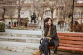 woman sitting on a bench in the park while using her mobile phone