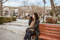 woman sitting on a bench in the park while using her mobile phone