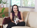 Asian woman sitting on couch in living room with her Chihuahua dog on lap smiling and looking at camera , stay home , social Royalty Free Stock Photo