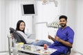 Asian woman sitting in the dentist& x27;s chair in light modern dental clinic with attractive man dentist Royalty Free Stock Photo