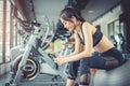 Asian woman sitting on fitness ball and listening music in fitness training gym with smart phone. Relax and sport workout Royalty Free Stock Photo