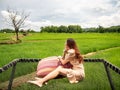 Asian woman sitting on hammock balcony looking away to dead tree in rice field. Royalty Free Stock Photo