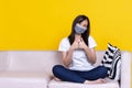 Asian woman sitting on sofa wearing face mask showing thumbup during