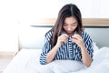 An Asian woman sitting on the white bed, She open her shirt and bent over to see her own breast size Royalty Free Stock Photo