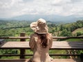 Asian woman sitting on wooden table in cafe with green mountain view. Nan, Thailand. Royalty Free Stock Photo