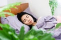 Asian woman sleeping peaceful with fresh air from green plants in bedroom