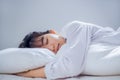 Asian woman sleeping well in bed hugging soft white pillow with blanket on white sheets in bedroom Royalty Free Stock Photo
