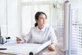 Asian woman smart architect look out the window to rest one's eyes or relax while working in light and bright office room,