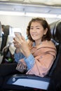 Asian woman with smart phone in hand sitting in air plane seat p Royalty Free Stock Photo