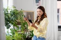 Asian woman with smartphone and flowers at home