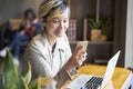 Young Asian woman smiling using smart phone and laptop at coffee shop Royalty Free Stock Photo