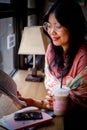 an Asian woman is reading a book in a cafe while holding an ice coffee latte Royalty Free Stock Photo