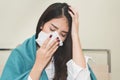 Asian woman sneeze on the bed. unhealthy young female have cold and high temperature from fever and sitting on the bed