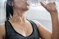 Asian woman in sportwear drinking fresh water from bottle after doing sport , sweating and tired from exercise