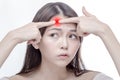 Asian woman squeezing glowing red spot on forehead Royalty Free Stock Photo