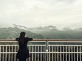 Asian woman standing alone on balcony looking at white foggy and mountains background
