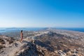 An Asian woman standing on the edge of a cliff overlooking the town of Pyrgos on Santorini island, Greece