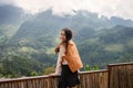 Asian woman standing and enjoying the mountain view on wooden balcony in sunny day Royalty Free Stock Photo