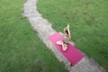 Asian woman standing on fitness mat, sporty lady practicing yoga at public park outdoor, stretching her body. Healthy
