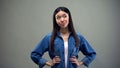 Asian woman standing on grey background, hesitating what to choose, decision