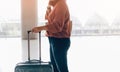 Asian woman standing and holding suitcase with waiting check in for the flight at the airport terminal